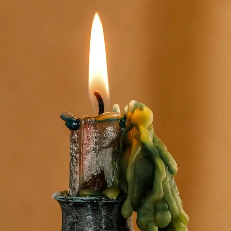 Lit green candle in a metal candelabra
